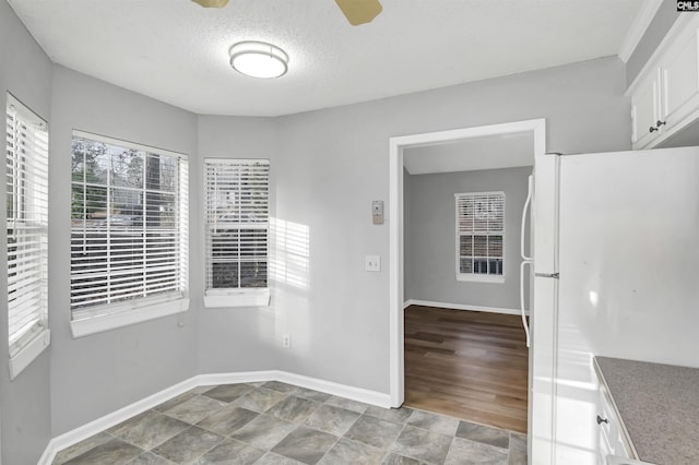 unfurnished dining area with ceiling fan and a textured ceiling