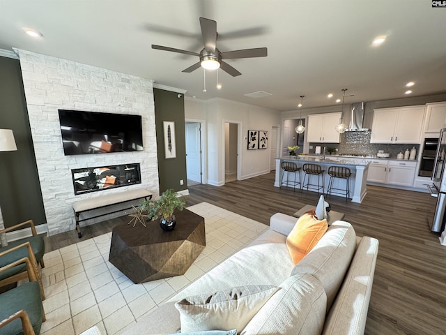 living area with a fireplace, baseboards, crown molding, and wood finished floors