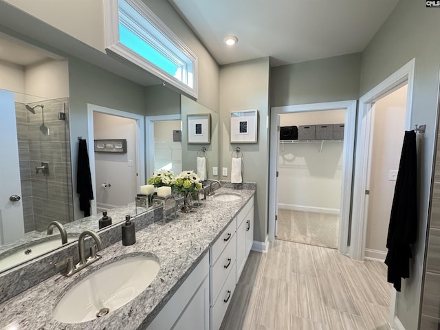 full bath with a spacious closet, double vanity, a stall shower, and a sink