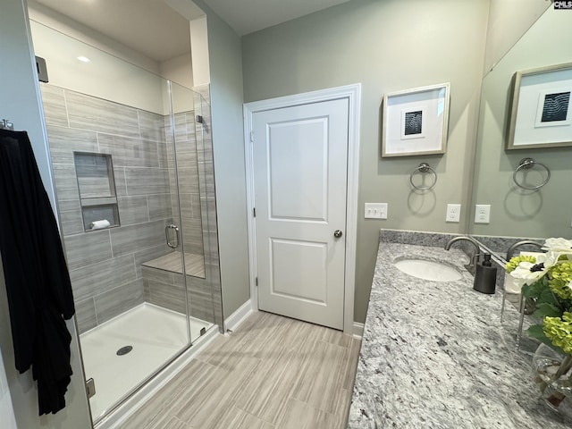 full bath with a stall shower, vanity, and baseboards