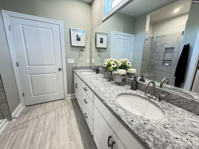 full bathroom featuring a stall shower, a sink, baseboards, and double vanity