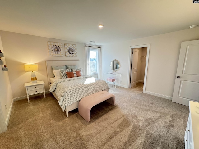 carpeted bedroom featuring baseboards and a walk in closet