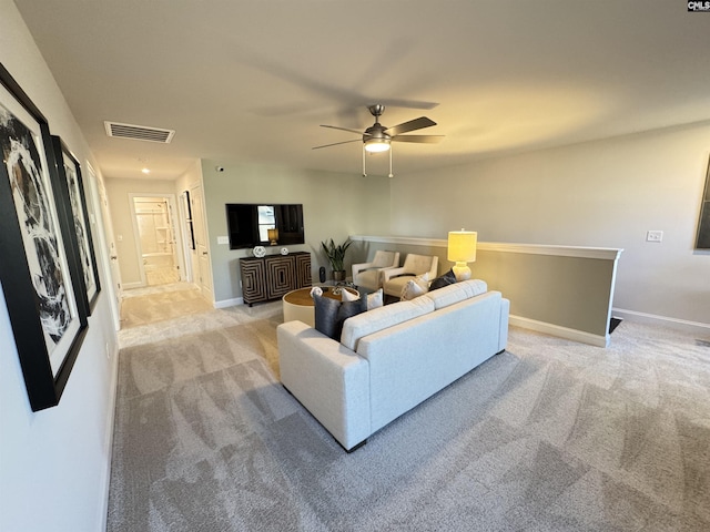 living room featuring baseboards, a ceiling fan, visible vents, and light colored carpet