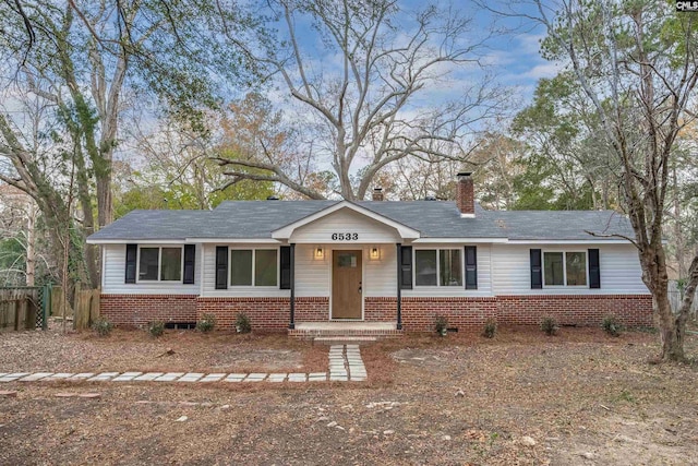 ranch-style home with a chimney, fence, and brick siding