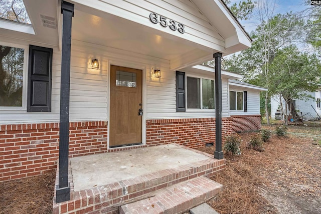 doorway to property featuring crawl space and brick siding