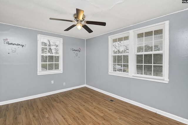 empty room featuring plenty of natural light, ceiling fan, and wood-type flooring