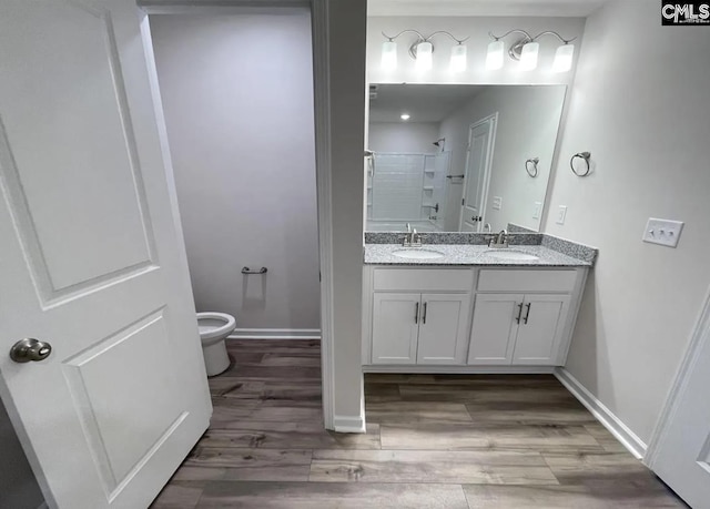 bathroom featuring toilet, a shower, wood-type flooring, and vanity