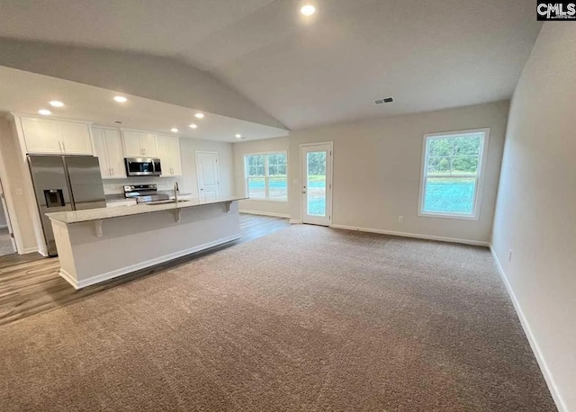 kitchen with white cabinetry, appliances with stainless steel finishes, a healthy amount of sunlight, and a center island with sink