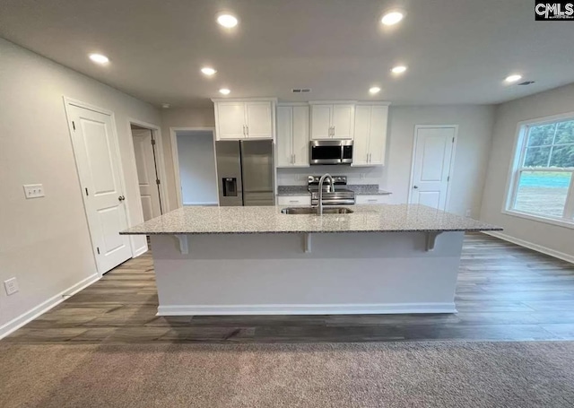 kitchen with a center island with sink, a kitchen bar, sink, white cabinetry, and appliances with stainless steel finishes