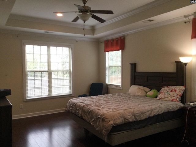 bedroom featuring dark wood-type flooring, ornamental molding, and a tray ceiling