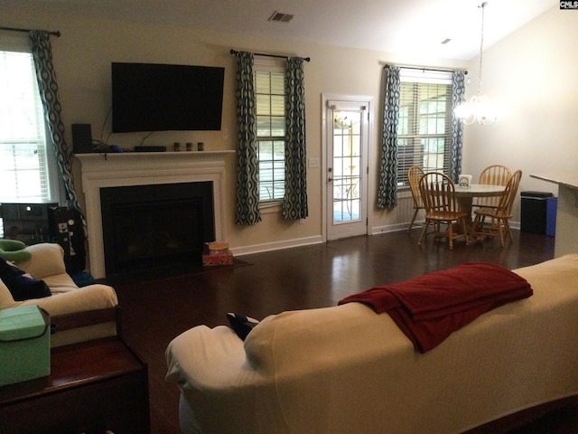 living room with an inviting chandelier, hardwood / wood-style floors, vaulted ceiling, and a healthy amount of sunlight