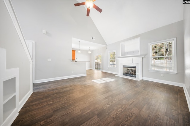 unfurnished living room with ceiling fan, a healthy amount of sunlight, dark hardwood / wood-style flooring, and high vaulted ceiling