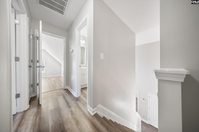 hallway featuring light hardwood / wood-style floors and vaulted ceiling