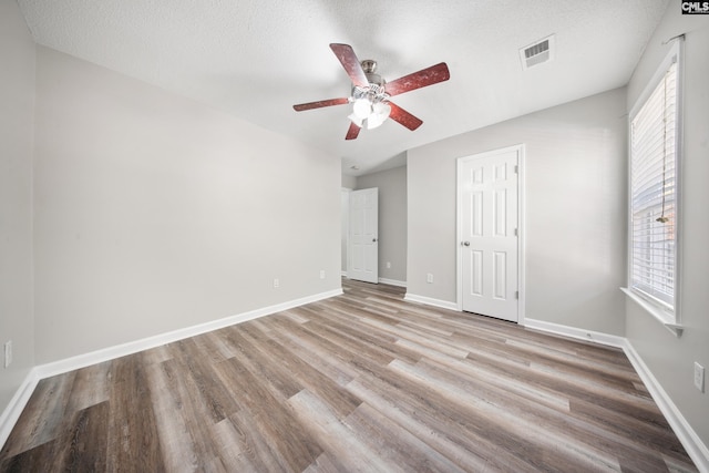 unfurnished bedroom featuring multiple windows, a textured ceiling, light hardwood / wood-style flooring, and ceiling fan