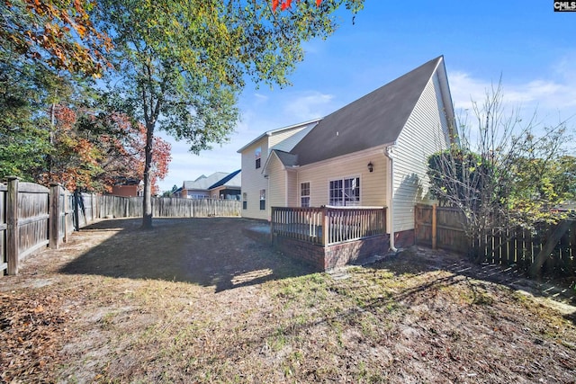 rear view of property featuring a wooden deck and a lawn