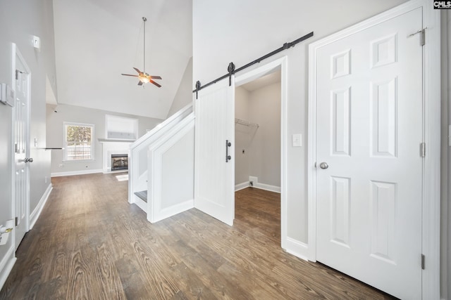 interior space featuring hardwood / wood-style flooring, ceiling fan, a barn door, and lofted ceiling