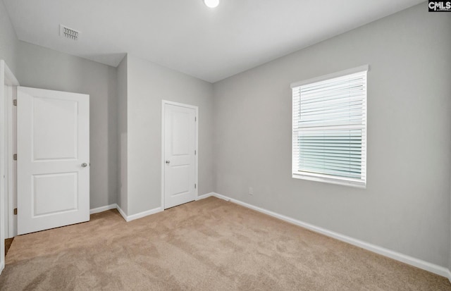 unfurnished bedroom featuring a closet and light colored carpet