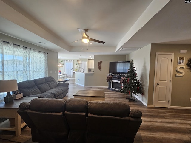 living room with a raised ceiling, ceiling fan, and wood-type flooring