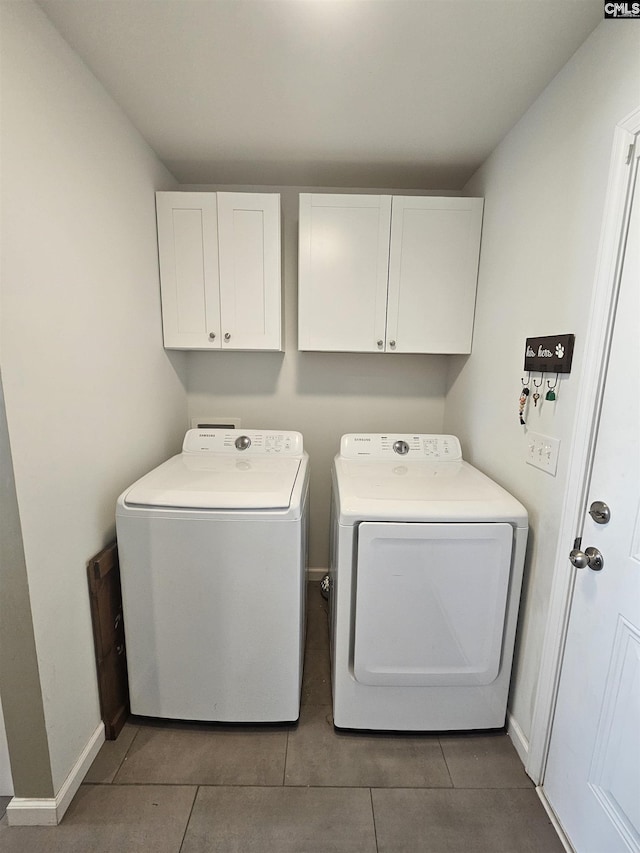 clothes washing area with dark tile patterned floors, cabinets, and separate washer and dryer