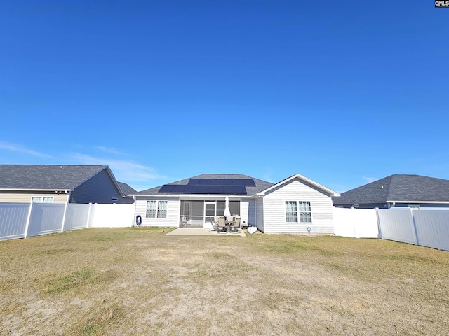 back of house with a lawn, a patio, and solar panels