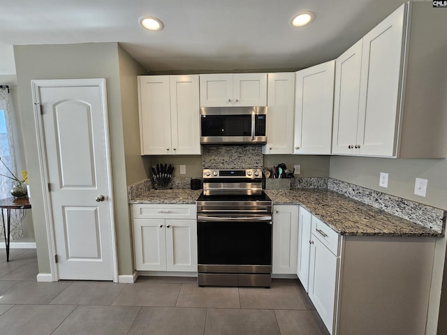 kitchen featuring dark stone countertops, white cabinetry, tile patterned flooring, and appliances with stainless steel finishes