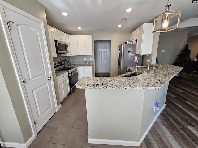 kitchen with white cabinetry, hanging light fixtures, stainless steel appliances, and sink