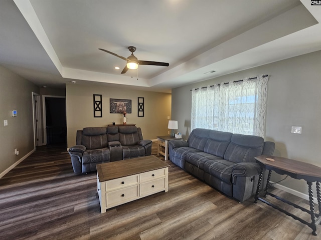 living room with a tray ceiling, ceiling fan, and dark hardwood / wood-style flooring