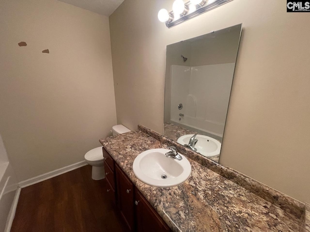 full bathroom featuring washtub / shower combination, hardwood / wood-style floors, vanity, and toilet