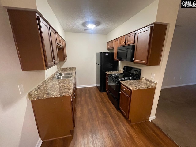 kitchen with dark hardwood / wood-style flooring, sink, black appliances, and a textured ceiling