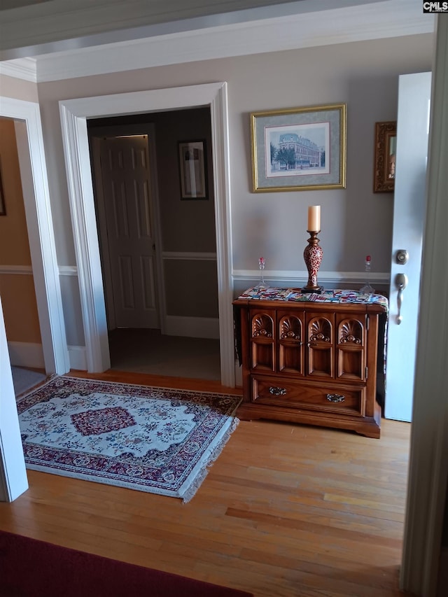 hallway with light hardwood / wood-style floors and crown molding