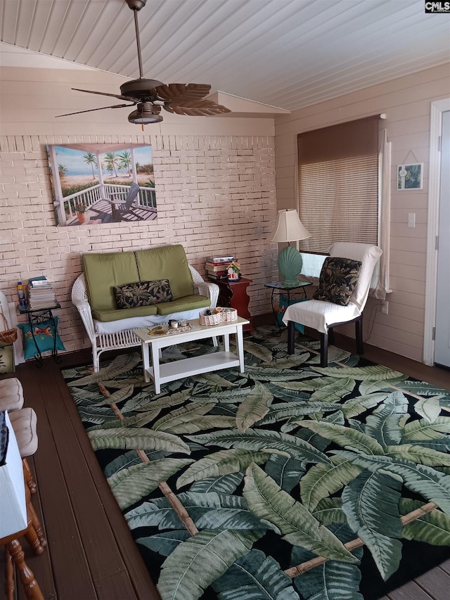 interior space featuring wood walls, ceiling fan, lofted ceiling, and brick wall