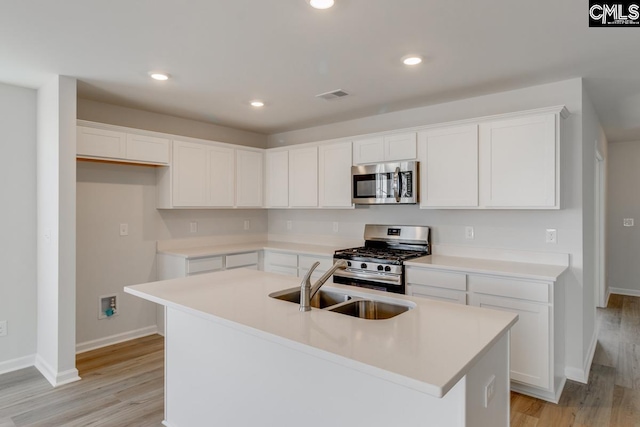 kitchen featuring a kitchen island with sink, sink, white cabinets, and appliances with stainless steel finishes