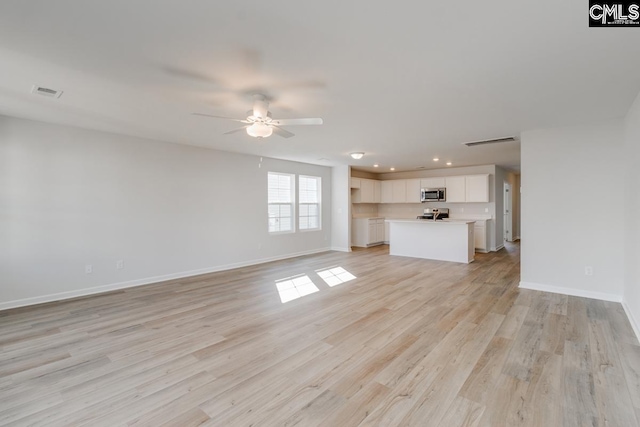 unfurnished living room featuring ceiling fan and light wood-type flooring