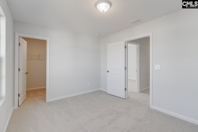 unfurnished bedroom with light colored carpet, a spacious closet, and a closet