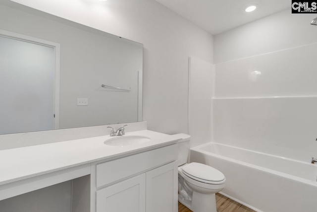 full bathroom featuring hardwood / wood-style floors, vanity, tub / shower combination, and toilet