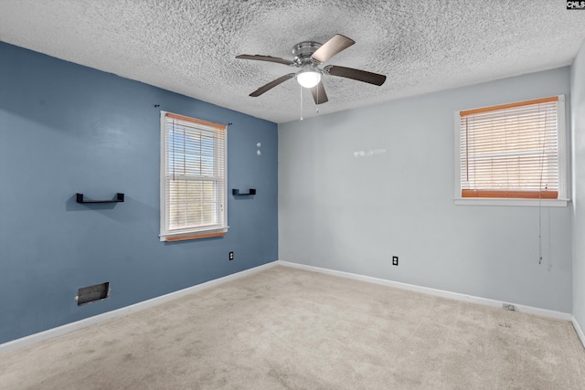 empty room with a textured ceiling, light colored carpet, and ceiling fan