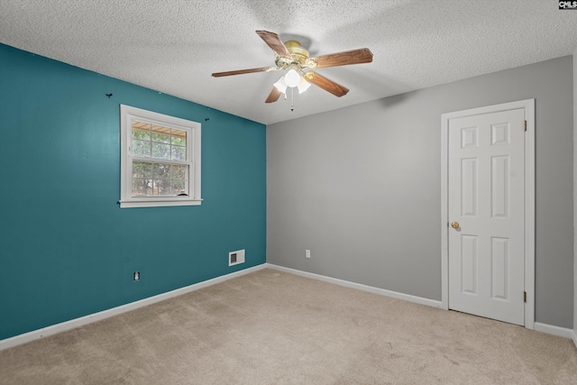 spare room featuring light carpet, a textured ceiling, and ceiling fan