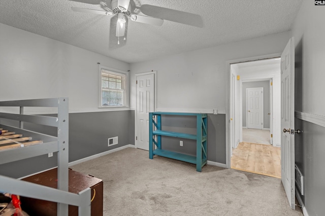 carpeted bedroom with ceiling fan and a textured ceiling