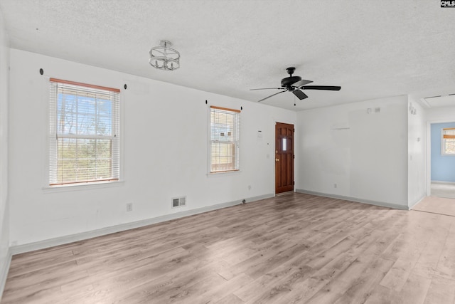 spare room with ceiling fan, light wood-type flooring, and a wealth of natural light