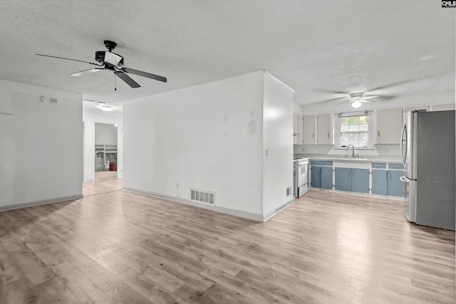 unfurnished living room featuring ceiling fan, light wood-type flooring, and a textured ceiling