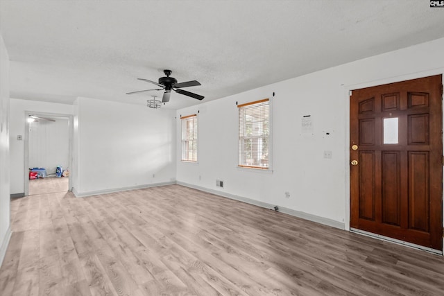 interior space with a textured ceiling, light wood-type flooring, and ceiling fan