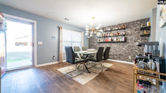 dining area with dark wood-type flooring and an inviting chandelier