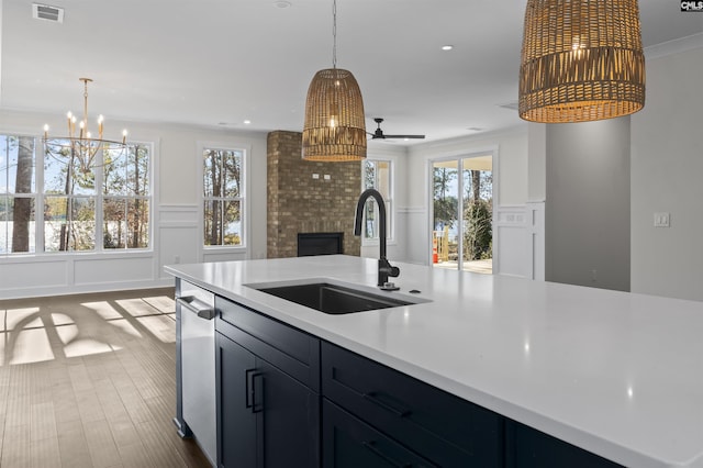 kitchen with a brick fireplace, ornamental molding, ceiling fan with notable chandelier, sink, and hanging light fixtures