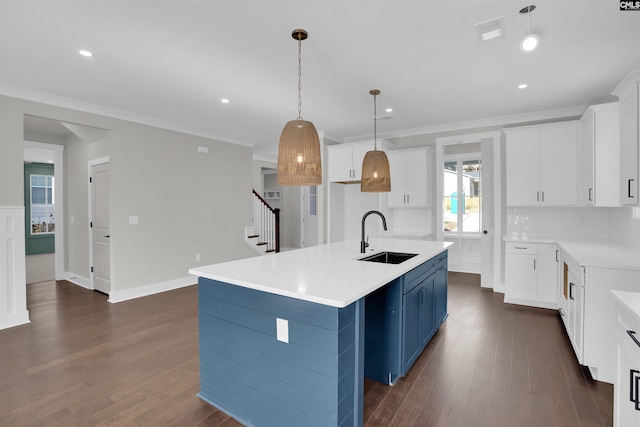 kitchen featuring a kitchen island with sink, sink, hanging light fixtures, and blue cabinets