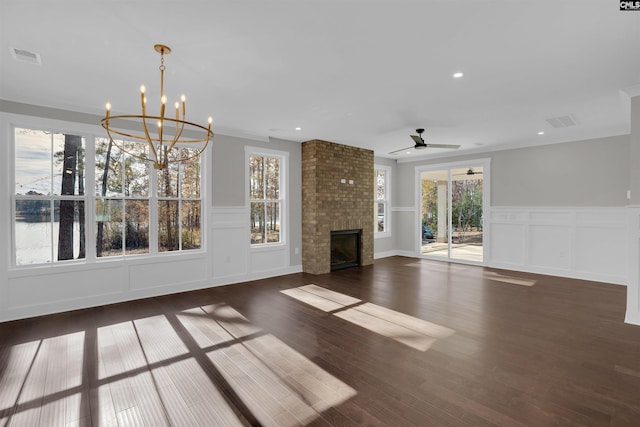 unfurnished living room with ceiling fan with notable chandelier, dark hardwood / wood-style flooring, plenty of natural light, and a fireplace