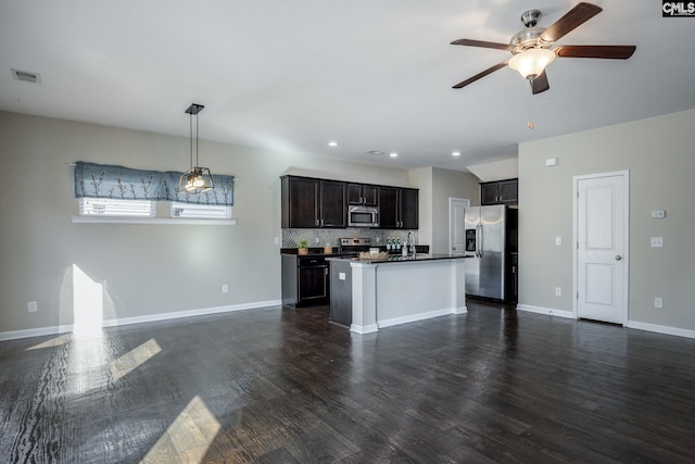 kitchen featuring backsplash, a kitchen island with sink, ceiling fan, appliances with stainless steel finishes, and decorative light fixtures