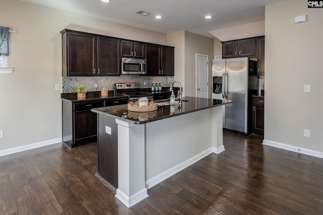 kitchen featuring appliances with stainless steel finishes, dark hardwood / wood-style flooring, tasteful backsplash, a kitchen island with sink, and sink