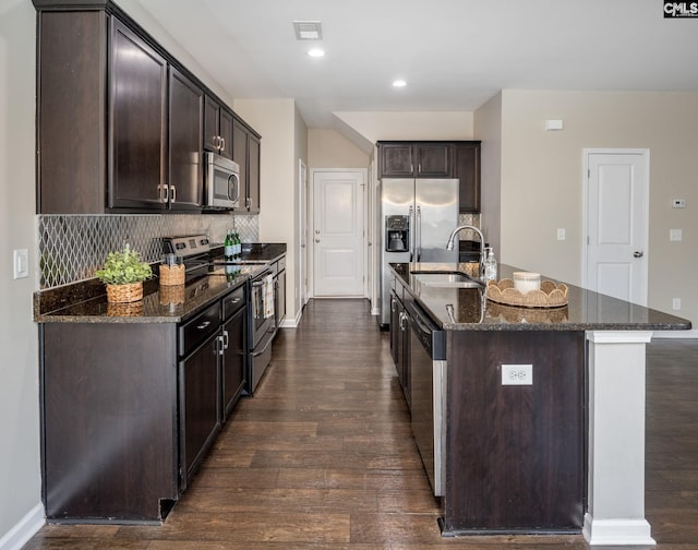 kitchen with a center island with sink, dark brown cabinets, sink, and appliances with stainless steel finishes