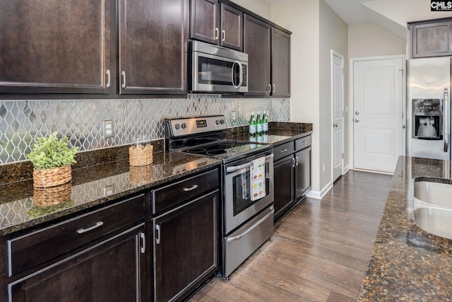 kitchen featuring dark stone counters, dark brown cabinets, stainless steel appliances, and dark hardwood / wood-style floors