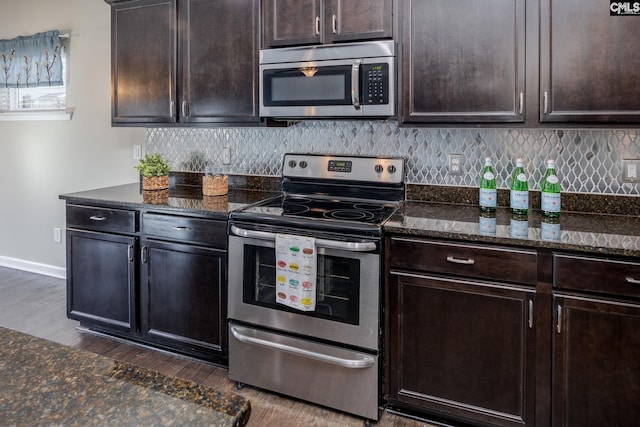 kitchen featuring appliances with stainless steel finishes, dark hardwood / wood-style floors, dark brown cabinets, and dark stone counters